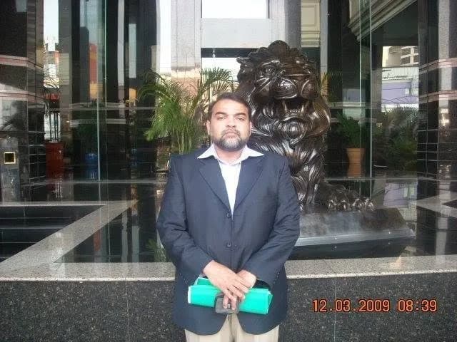 Prix Pharmaceutica founder standing beside a lion statue at a building entrance during an international business visit